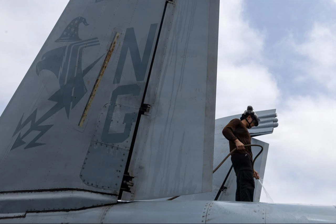 A U.S. Sailor washes an EA-18G Growler on the flight deck of Nimitz-class aircraft carrier USS Abraham Lincoln (CVN 72), Aug. 9, 2026. (Photo via U.S. Navy)