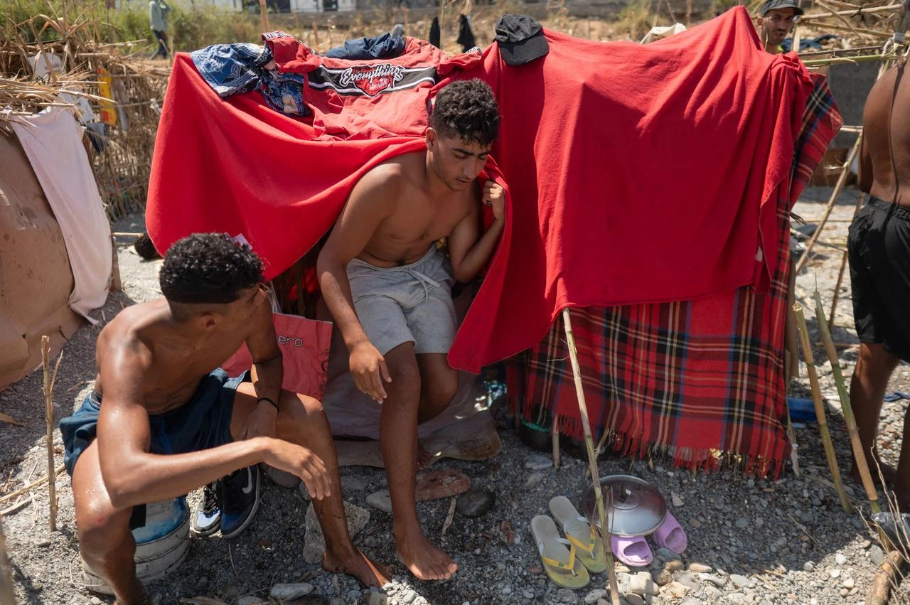 Migrants are pictured next to makeshift tents as they wait to enter a short-stay migrants centre, CETI, at Trampolin beach in Spain's north African Ceuta enclave on August 15, 2026.(AFP Photo)