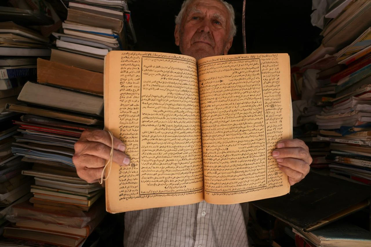 Rizkullah Abd, a 91-year-old bookseller, showing one of the books from his store. (AA Photo)