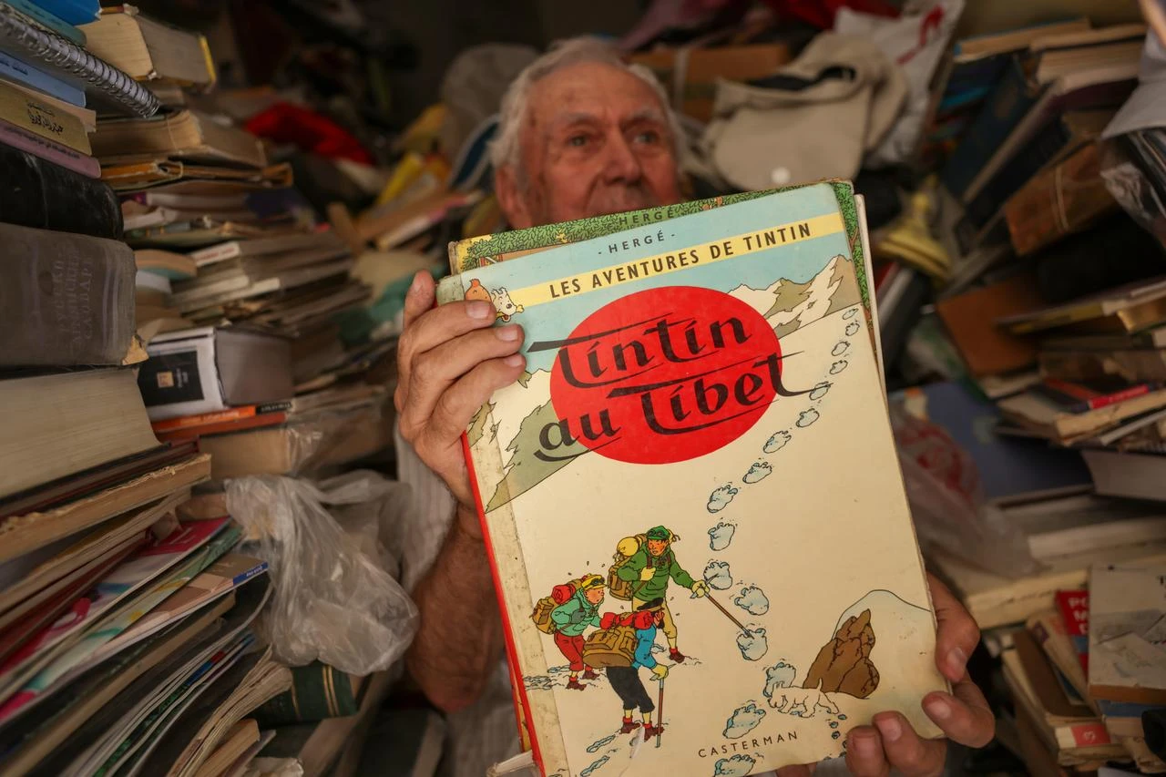 Rizkullah Abd, a 91-year-old bookseller, showing one of the books from his store. (AA Photo)
