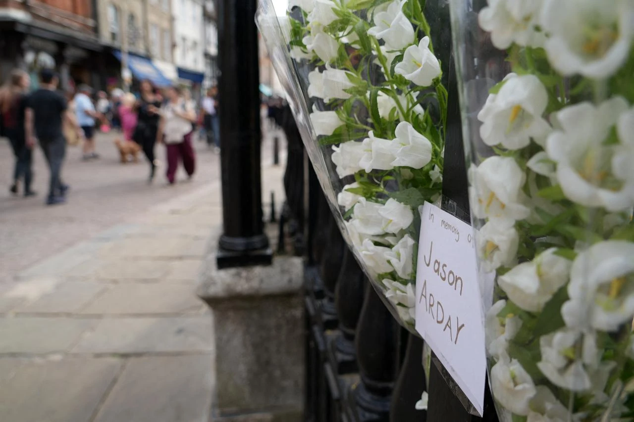 Members of the public walk past floral tributes to remember academic Jason Arday, attached to the railings outside Senate House in the University of Cambridge in Cambridge, eastern England, on August 15, 2026. (AFP Photo)