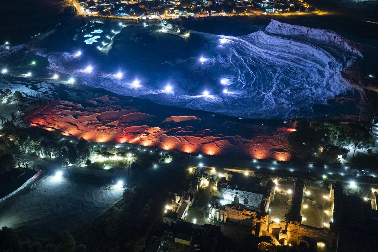 Pamukkale's illuminated white travertine terraces and nearby ancient ruins are seen at night in Denizli, Türkiye, Aug. 13, 2026. (AA Photo)
