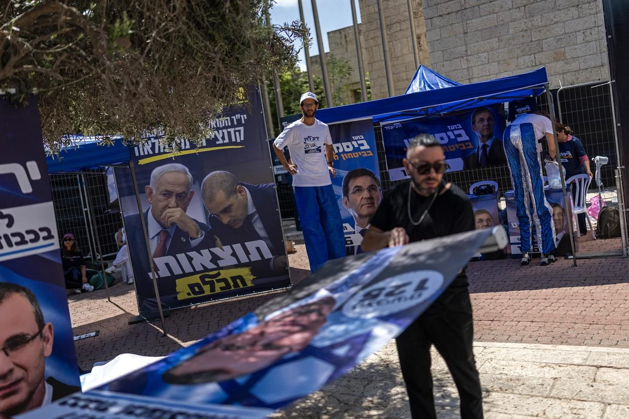 Supporters of Likud party stand amid stalls and posters installed outside a polling station during primary elections of their party ahead of country's national elections, in Jerusalem on August 17, 2026. (AFP Photo)