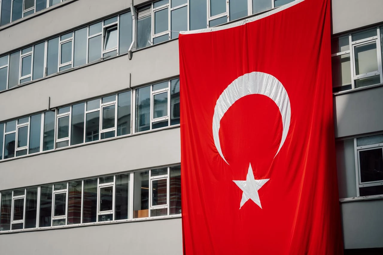 A Turkish flag hangs on the exterior of an office building in Türkiye. (Adobe Stock Photo)