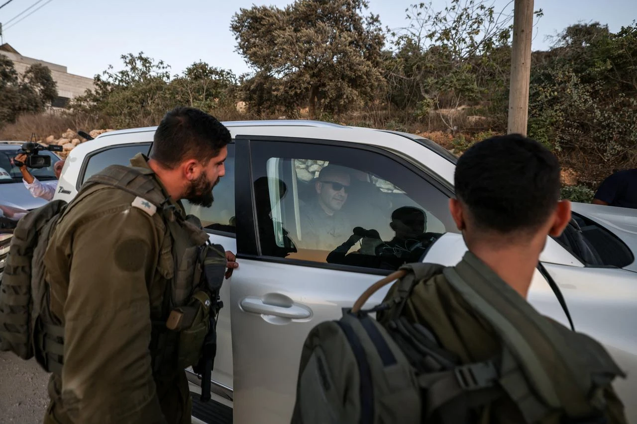 Israeli soldiers watch as US-Palestinian dual citizen Louai Abu Ridi, whose home in the Israeli-occupied West Bank village of Qusra is besieged by Israeli illegal settlers, arrives by car to visit his mother at her home in the same village, south of the Palestinian city of Nablus, upon his arrival from the US, on August 17, 2026. (AFP Photo)
