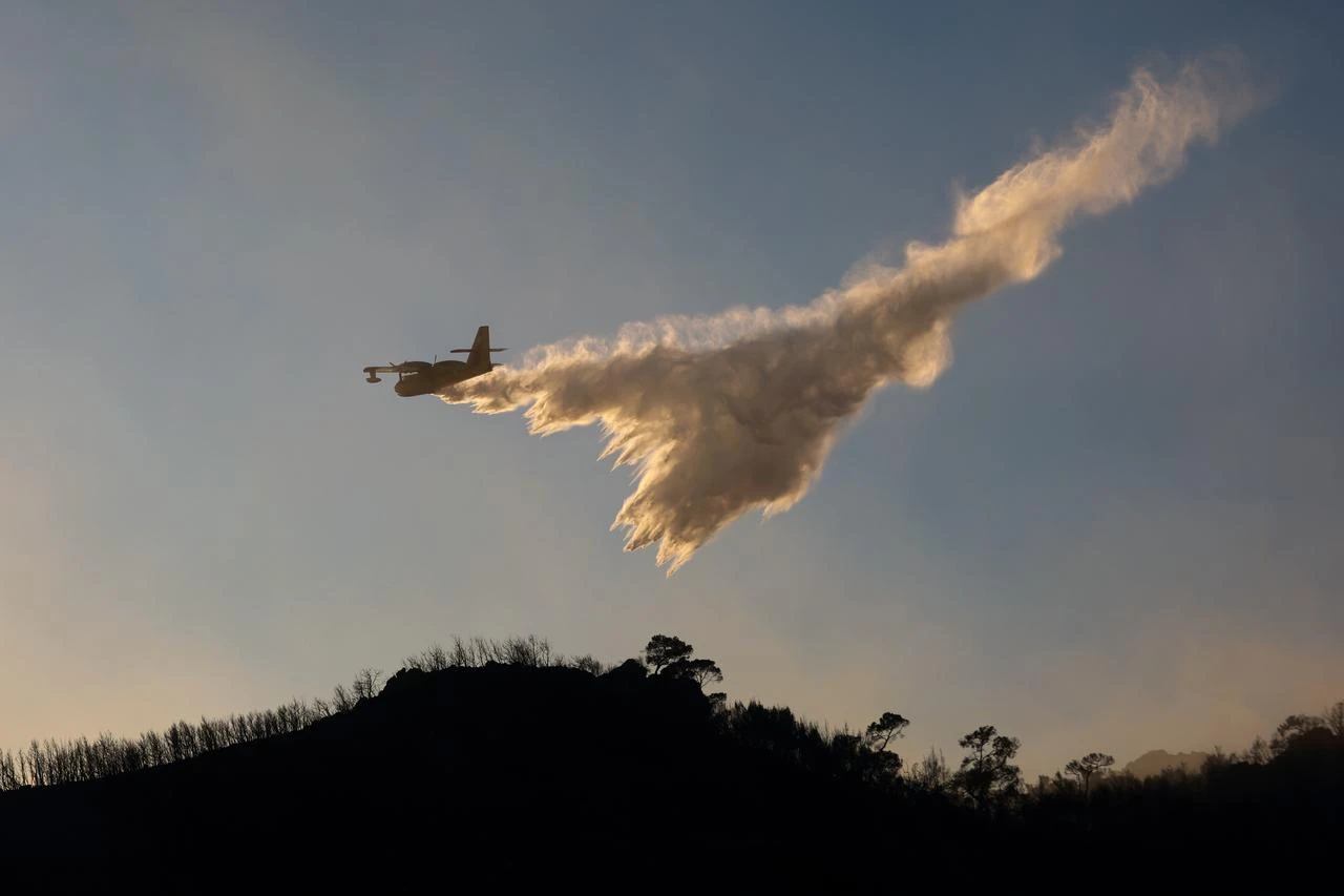 A firefighting aircraft drops water while battling a wildfire on Salamina Island, near Athens, Greece, Aug. 16, 2026. (AA Photo