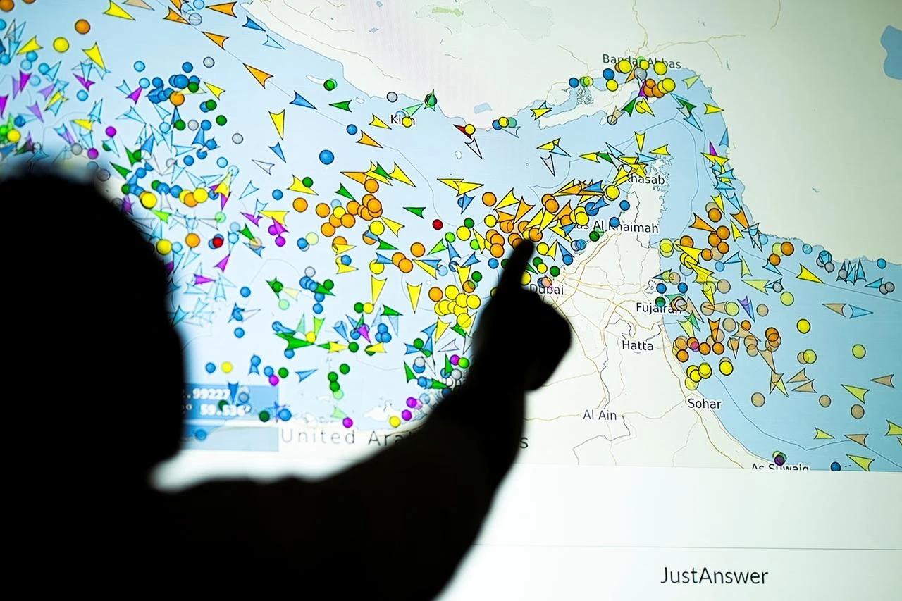 A photo illustration taken in Nicosia on May 4, 2026, shows a person in front of a large screen displaying vessel movements in the Strait of Hormuz on a ship-tracking website. (AFP File Photo)