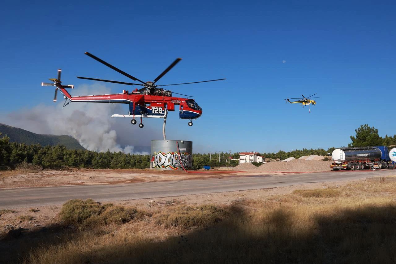 A firefighting helicopter reloads water while battling a wildfire near Porto Germeno, 70 kilometers northwest of Athens in the region of Viotia, Greece, August 2, 2026 (AA Photo)