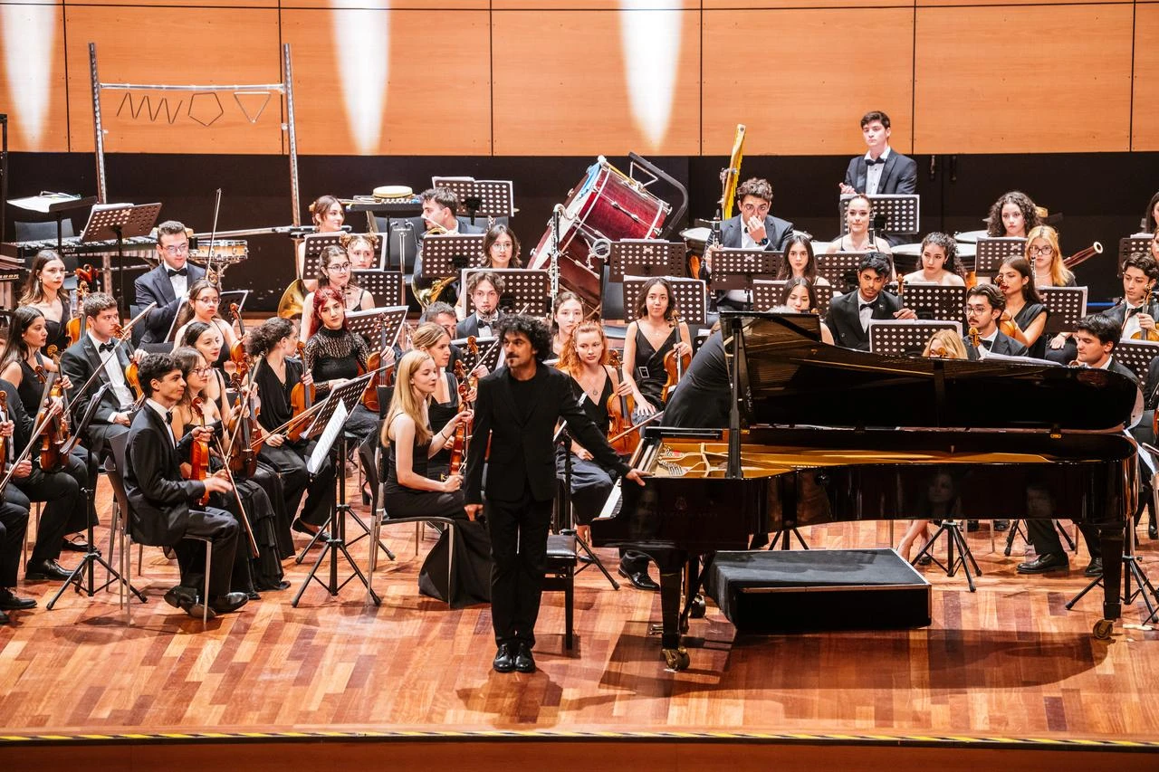 A pianist acknowledges the audience beside a grand piano during the Türkiye Youth Philharmonic Orchestra’s 20th-anniversary concert in Istanbul, Türkiye, Aug. 1, 2026. (AA Photo)