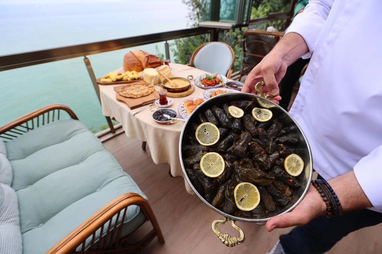 Chef displaying traditional Trabzon dish with Black Sea backdrop. (AA Photo)
