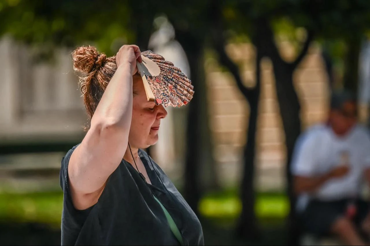 A woman shields herself from the sun with a hand fan during a heat wave in Athens, Greece, July 21, 2026. (AFP Photo)