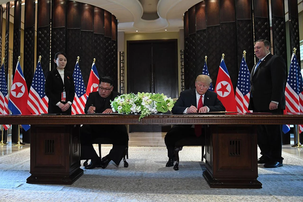US President Donald Trump (2nd R) and North Korea's leader Kim Jong Un (2nd L) sign documents as US Secretary of State Mike Pompeo (R) and the North Korean leader's sister Kim Yo Jong (L) look on at a signing ceremony during their historic US-North Korea summit, at the Capella Hotel on Sentosa island in Singapore, June 12, 2018. (AFP Photo)