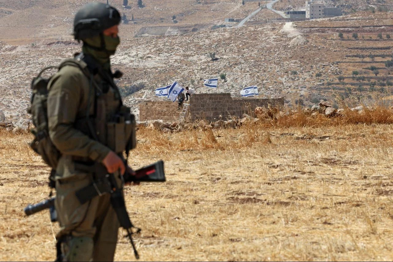 An Israeli soldier stands against the backdrop of a house seized by Israeli illegal settlers in Beit Sahur, south of Bethlehem, in the occupied West Bank on August 14, 2026. (AFP Photo)