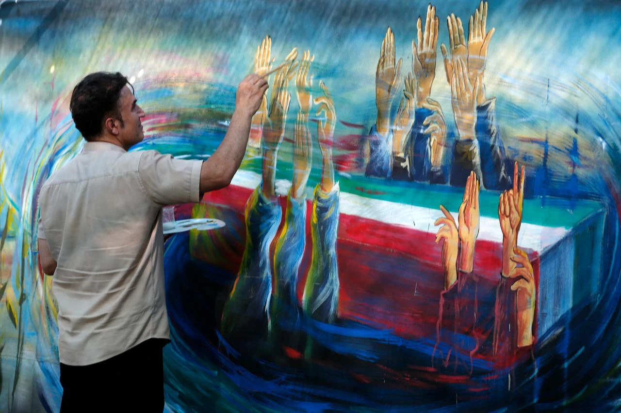A man paints a wall as people gather for commemoration ceremony marking the 40th day since the death of Ali Khamenei, who was killed in a joint US-Israeli airstrike, at the Imam Khomeini Mosalla Mosque in Tehran, Iran on August 18, 2026. (AA Photo)