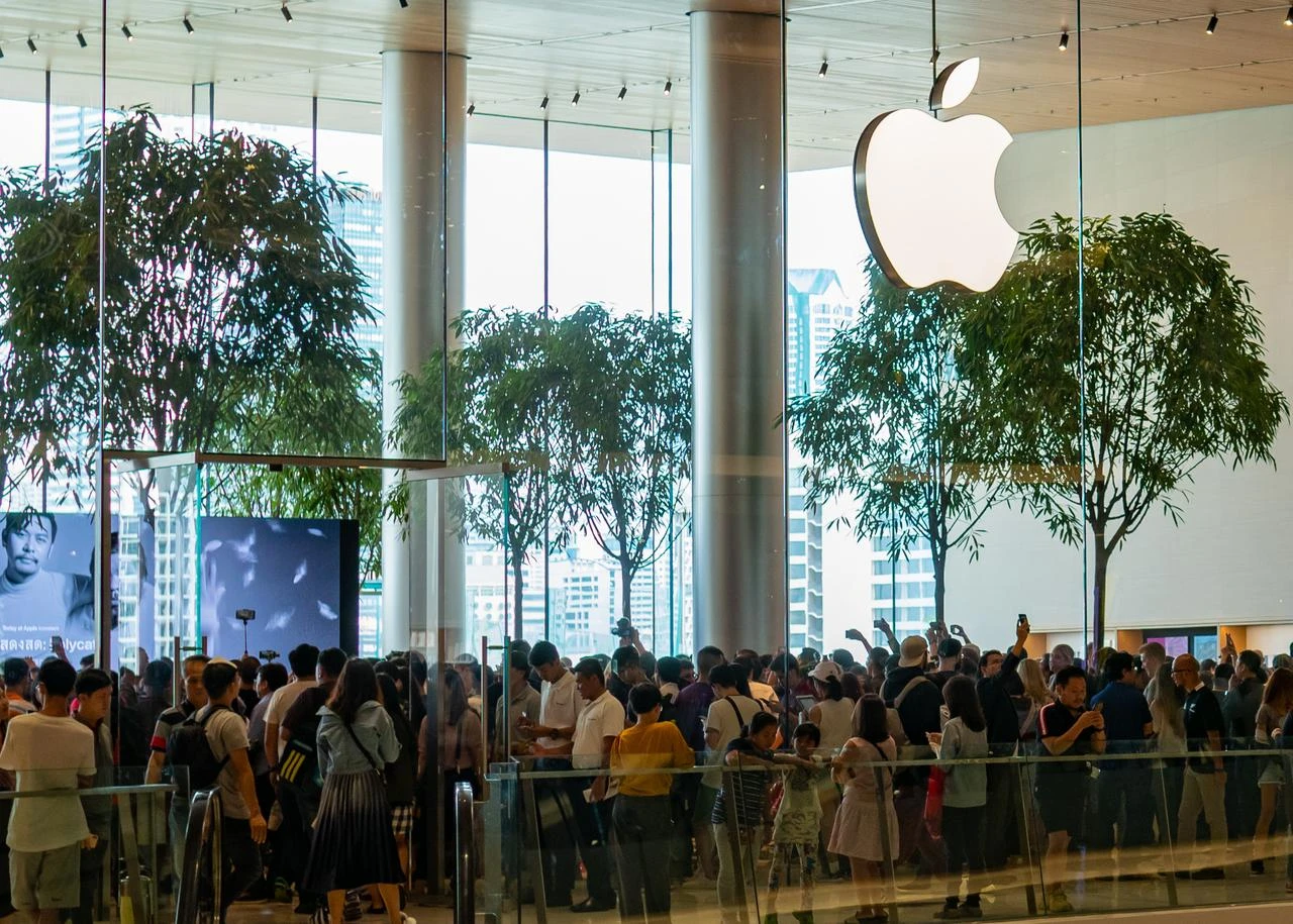 Customers gather inside an Apple Store beneath the company’s logo. (Adobe Stock Photo)