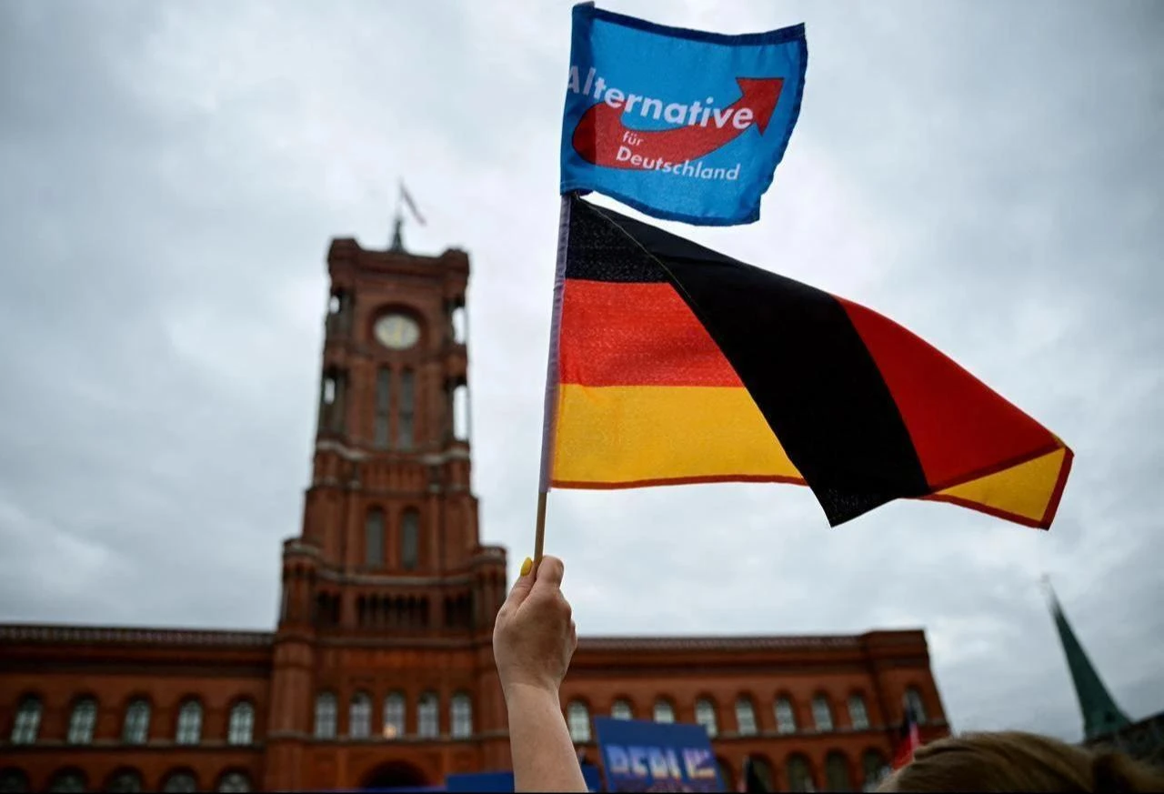 A supporter of the far-right Alternative for Germany (AfD) party waves their party's flag and a German flag at a campaign rally in front of the Berlin City Hall, June 29, 2026. (AFP Photo)