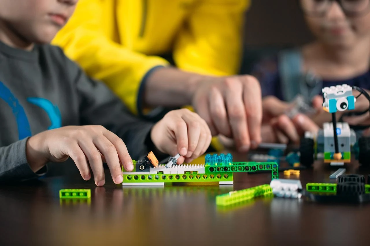 Kids build robots with a teacher at the table. (Adobe Stock Photo)