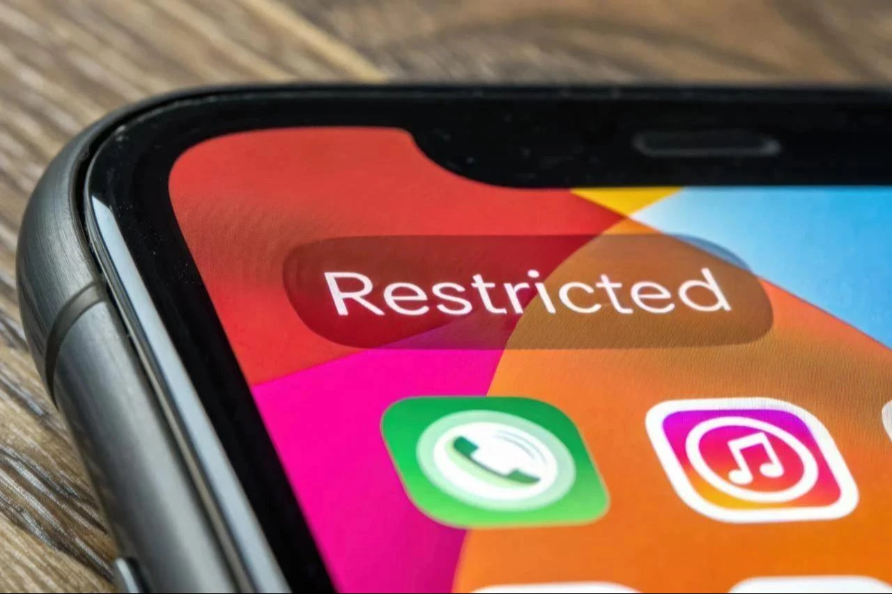 Smartphone screen displays Restricted notification on social media app icon. (Photo via Adobe Stock)