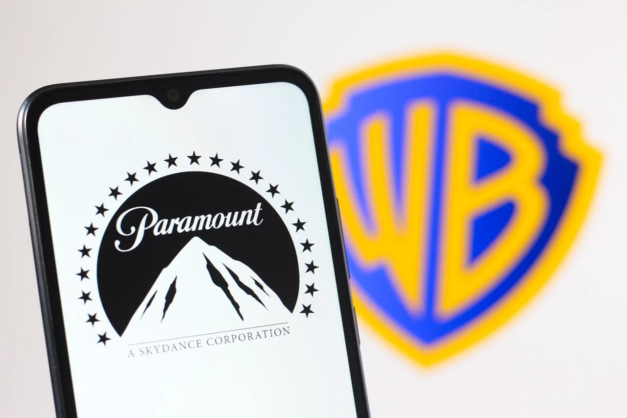 The Paramount logo is displayed on a smartphone screen with a Warner Bros. logo in the background. (Adobe Stock Photo)