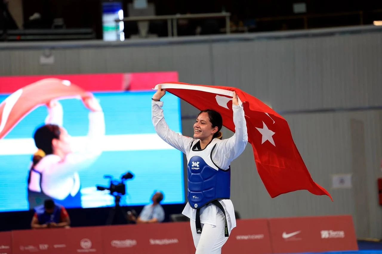 Taekwondo athlete Sude Yaren Uzuncavda celebrates with the national flag after a victory at the 20th Mediterranean Games in Massafra, Italy, Aug. 23, 2026. (AA Photo