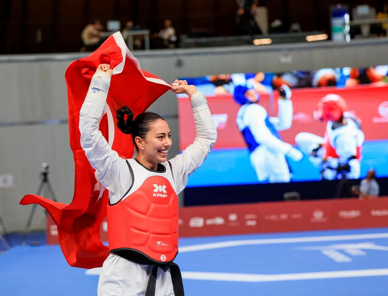 Taekwondo athlete Isıl Zafer celebrates with the national flag following a bout at the 20th Mediterranean Games in Massafra, Italy, Aug. 23, 2026. (AA Photo)