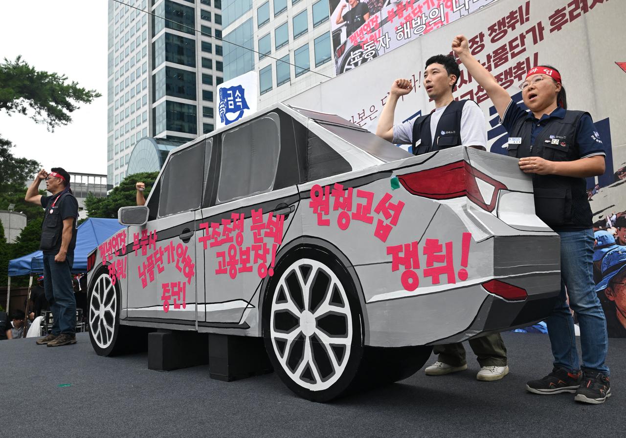 Members of the Korean Metal Workers' Union shout slogans next to a mock vehicle during a joint strike rally in front of the Hyundai Motor headquarters in Seoul on August 21, 2026. (AFP Photo)