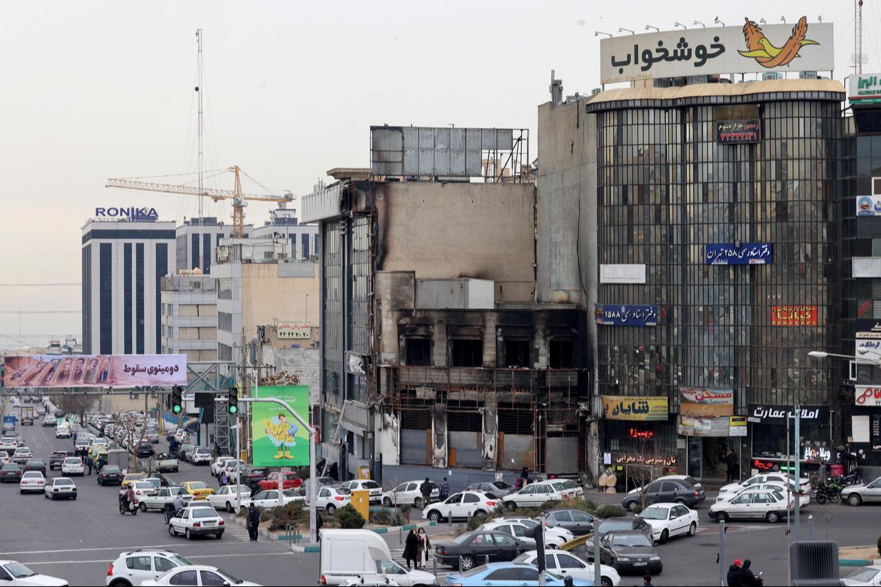 Vehicles drive past a burnt out building destroyed during public protests in the Iranian capital Tehran on January 19, 2026. (AFP Photo)