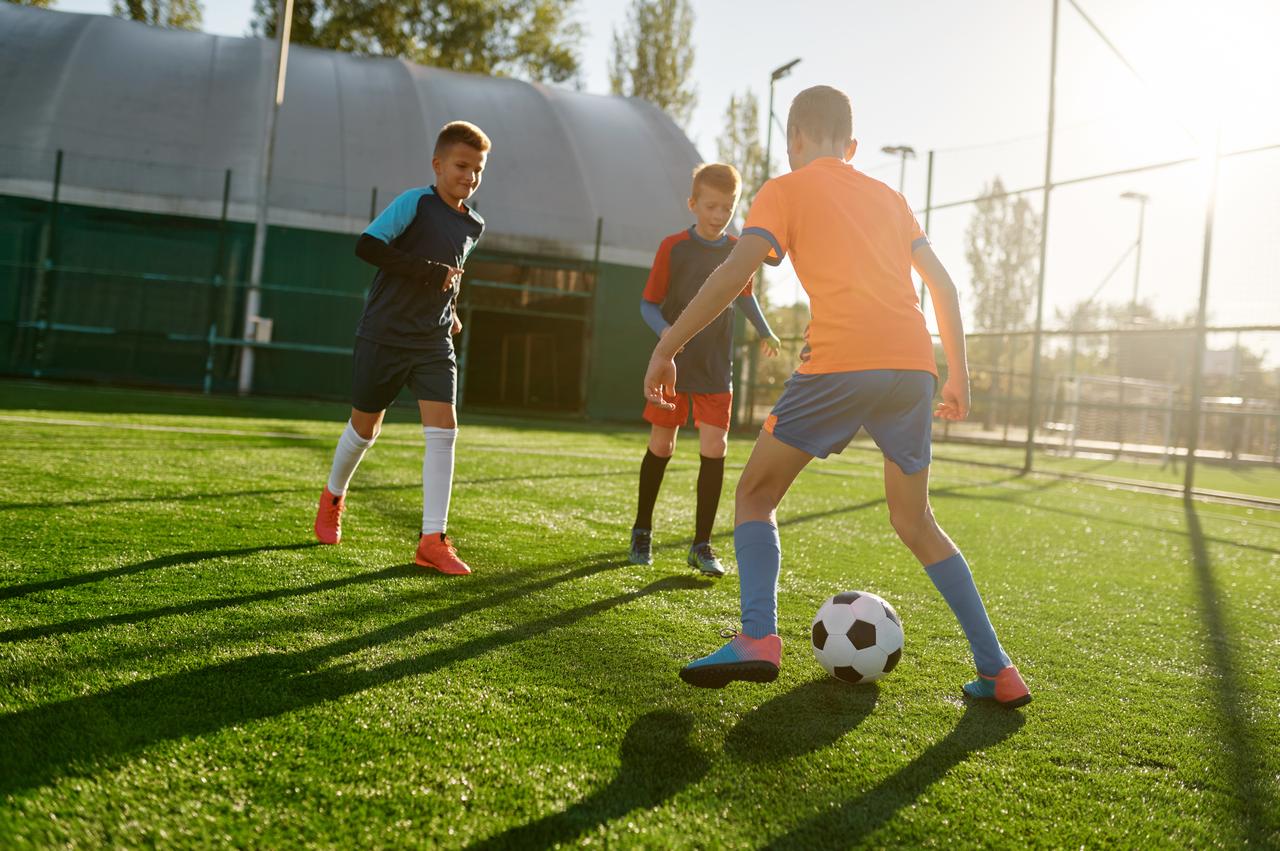 Children play soccer during a training session on an outdoor field. (Adobe Stock Photo)