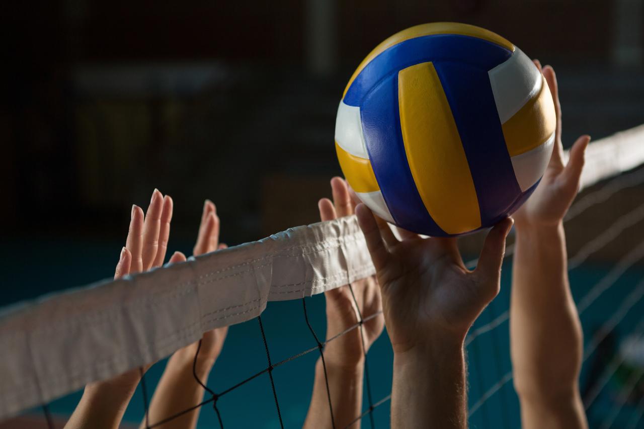 Players contest the ball at the net during a volleyball match. (Adobe Stock Photo)