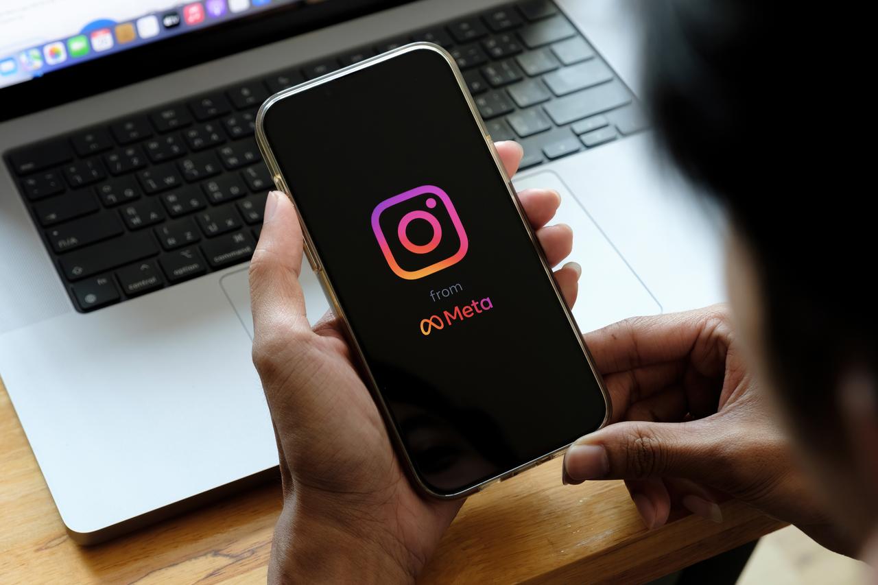 A man holds iPhone with Instagram application on the screen at cafe. (Photo via Adobe Stock)