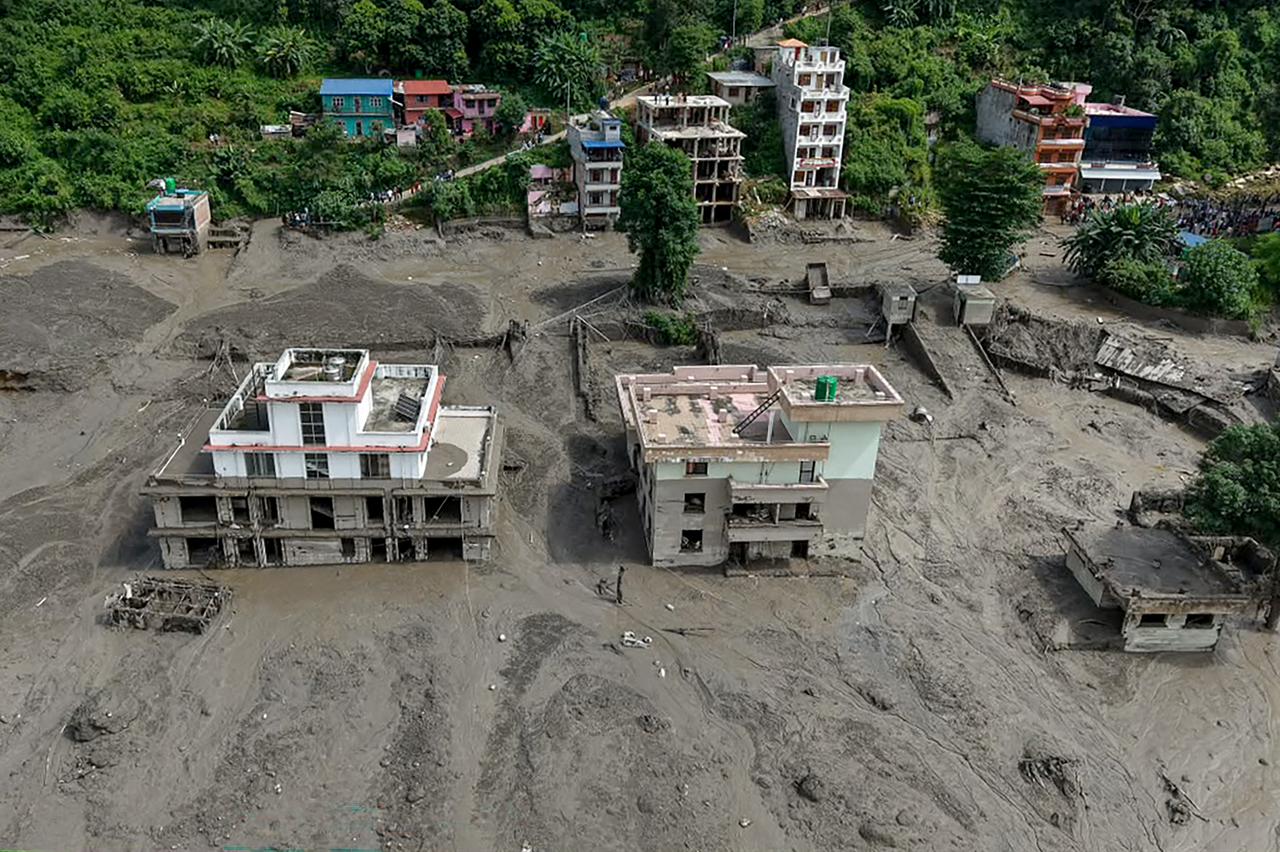 Houses lie partially submerged in muddy water along a riverside after flash floods at Trishuli Bazar in Nepal's Nuwakot district on August 26, 2026. (AFP Photo)