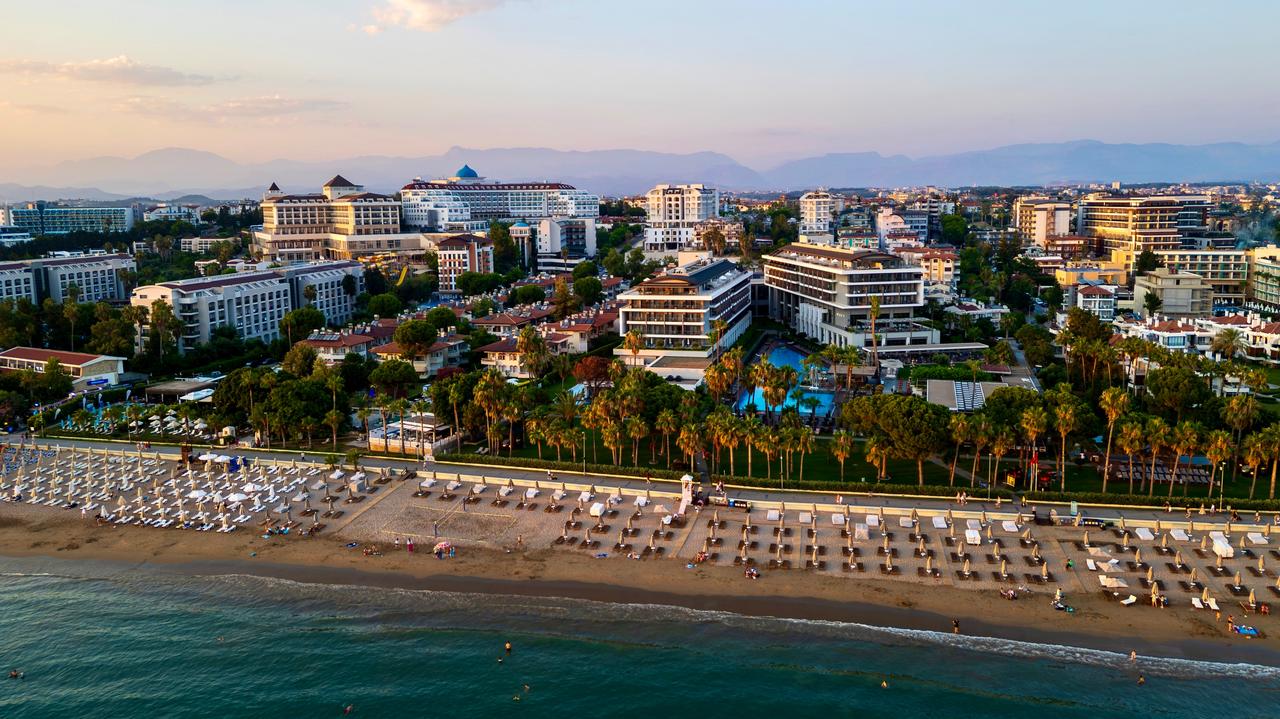 Aerial view shows a sandy beach lined with sunbeds and umbrellas, coastal hotels, and palm trees in Side, Antalya, Türkiye, July 17, 2026. (Adobe Stock Photo)