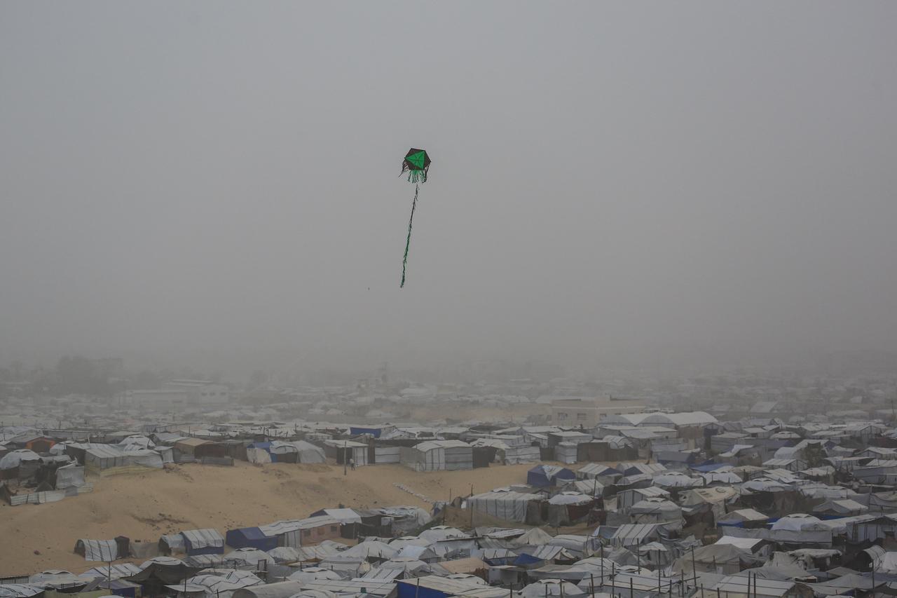 A kite flies over tents and makeshift shelters at a camp for displaced Palestinians during hazy and dusty weather in Khan Yunis, in the southern Gaza Strip, on February 14, 2026. (AFP Photo)
