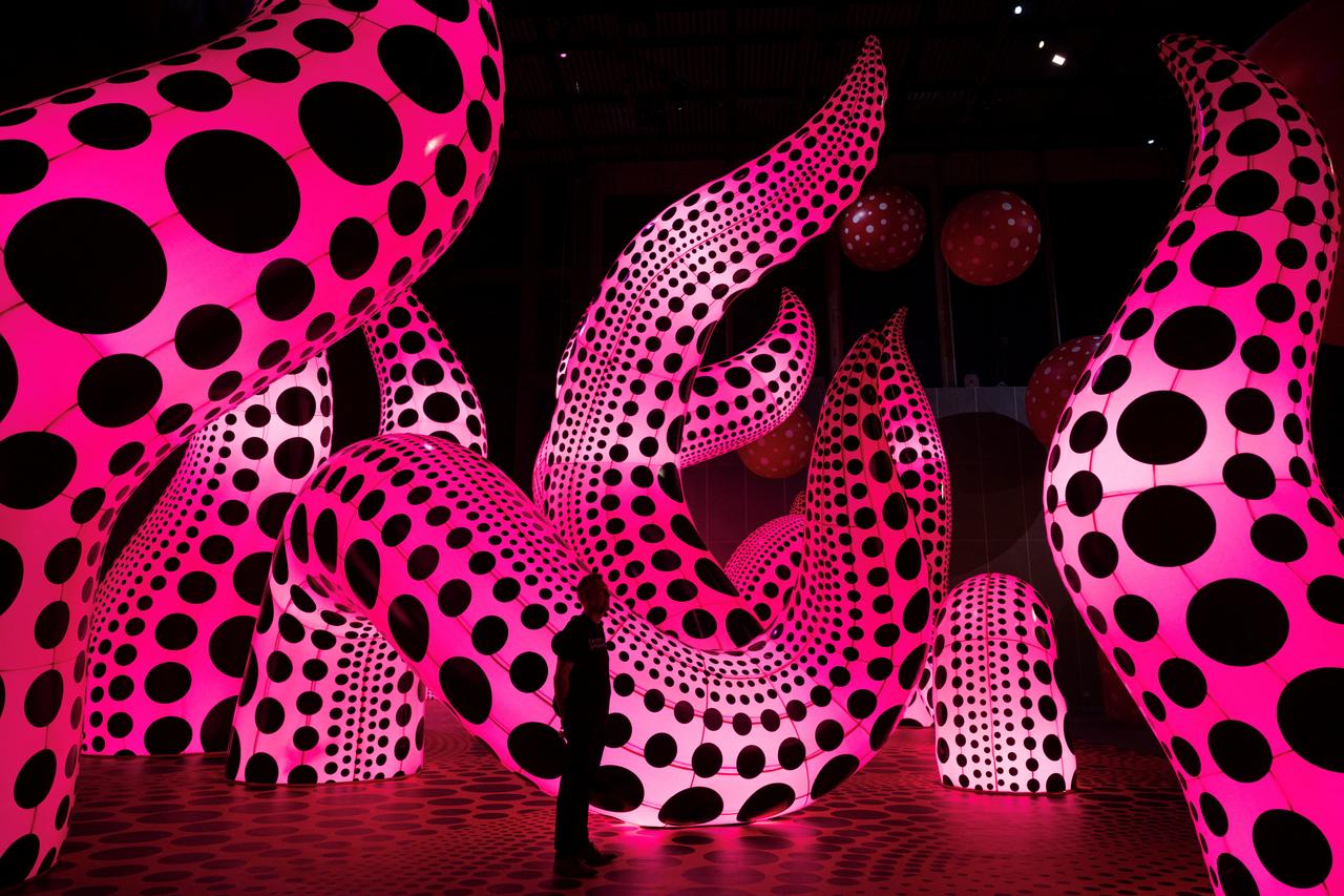 A visitor stands among illuminated polka-dot sculptures by Japanese artist Yayoi Kusama entitled 'You, Me and the Balloons' in the Aviva Studios gallery in Manchester, England, June 29, 2023. (AFP Photo)
