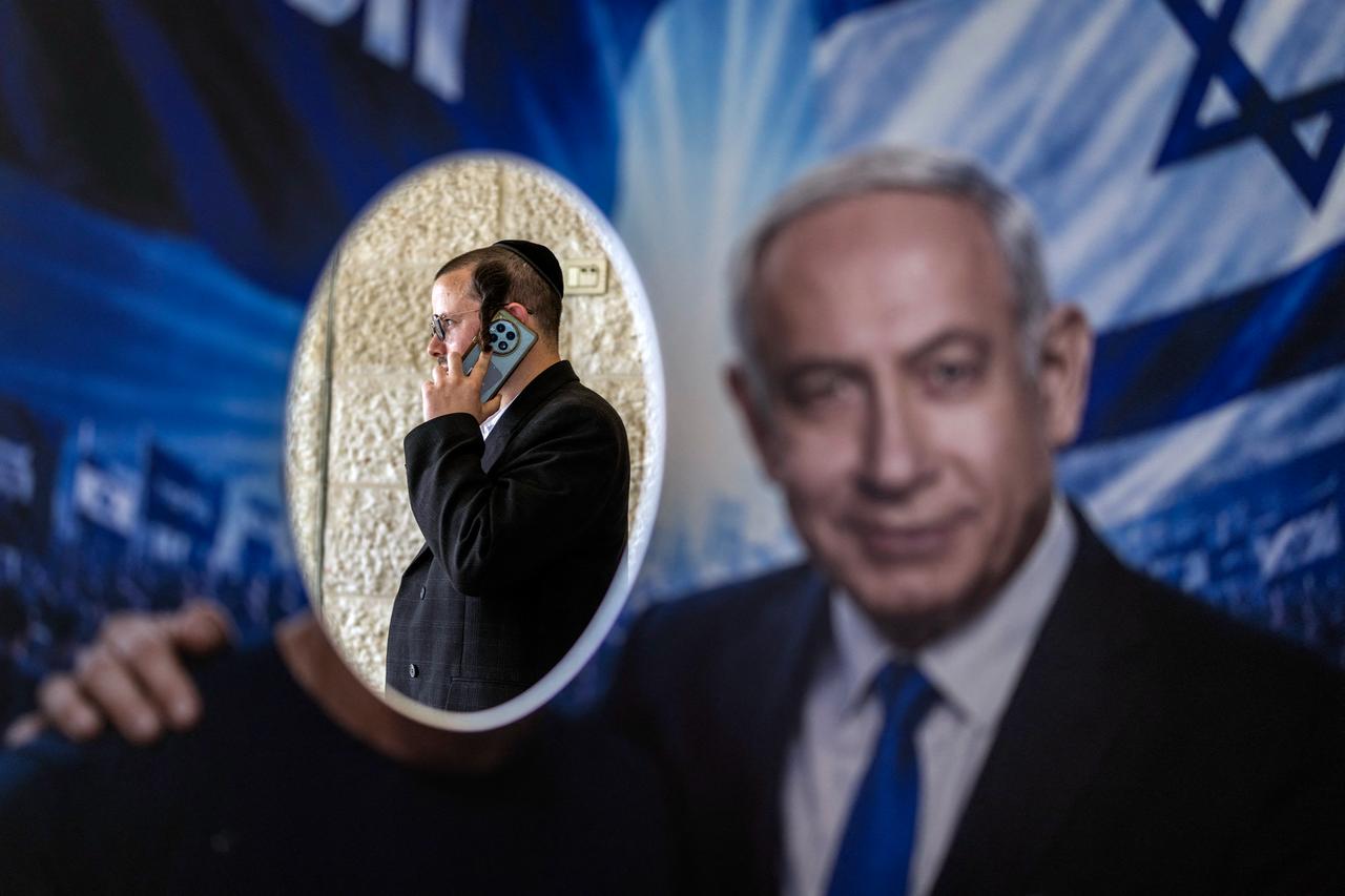 A member of Likud party is pictured through a poster with an image of Israeli Prime Minister Benjamin Netanyahu, at a polling station during primary elections of the party ahead of country's national elections, in Jerusalem on August 17, 2026. (AFP Photo)