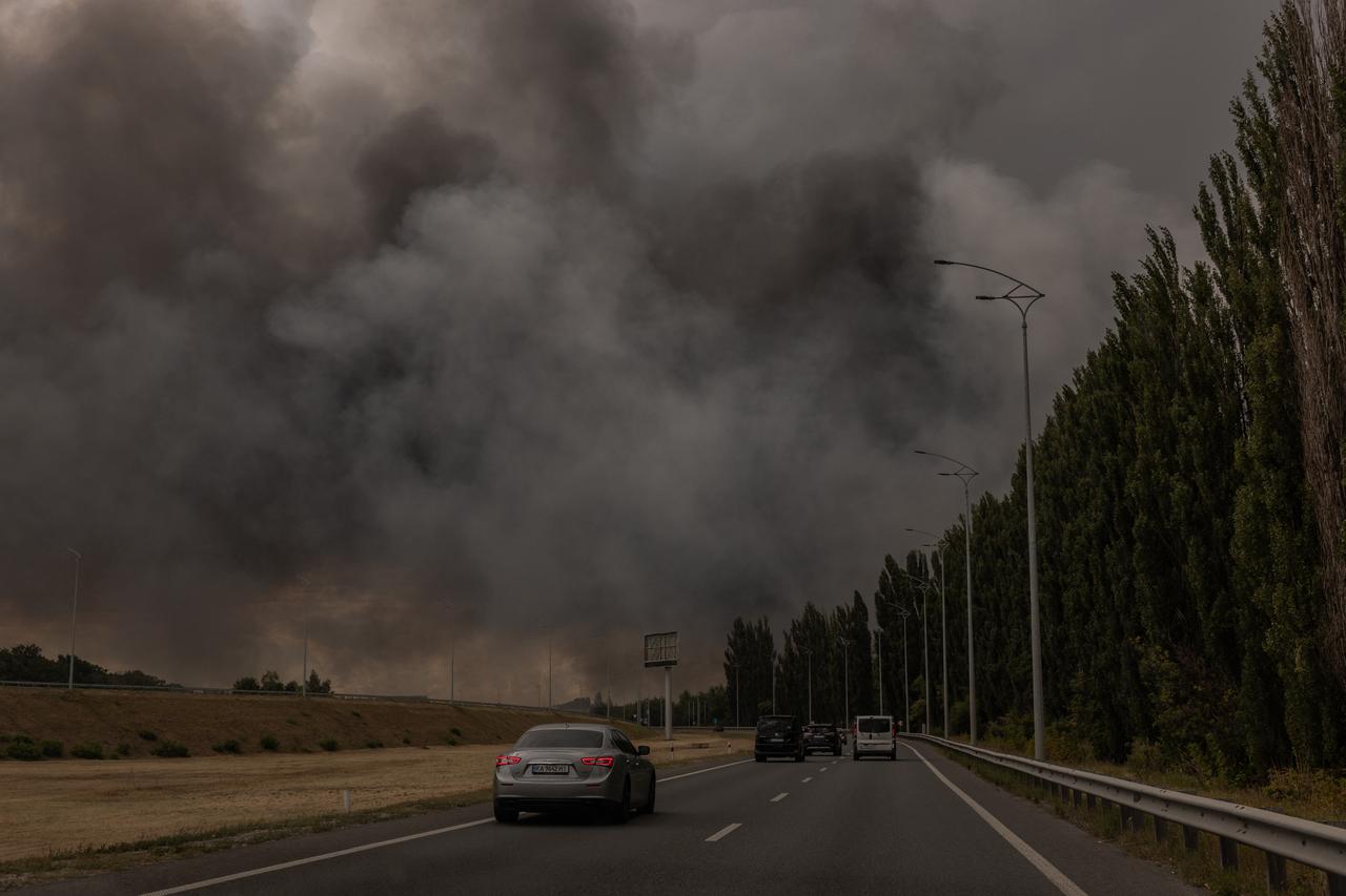 Cars drive on a road as smoke rises in the distance from a warehouse following a Russian air attack near Boryspil, Kyiv region on August 27, 2026. (AFP Photo)