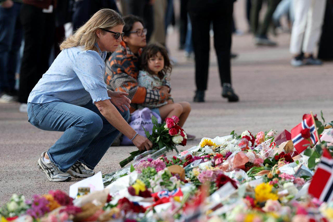 A woman lays a flower to pay tribute to King Harald V of Norway who passed away, at the Royal Palace square in Oslo on August 28, 2026. (AFP Photo)