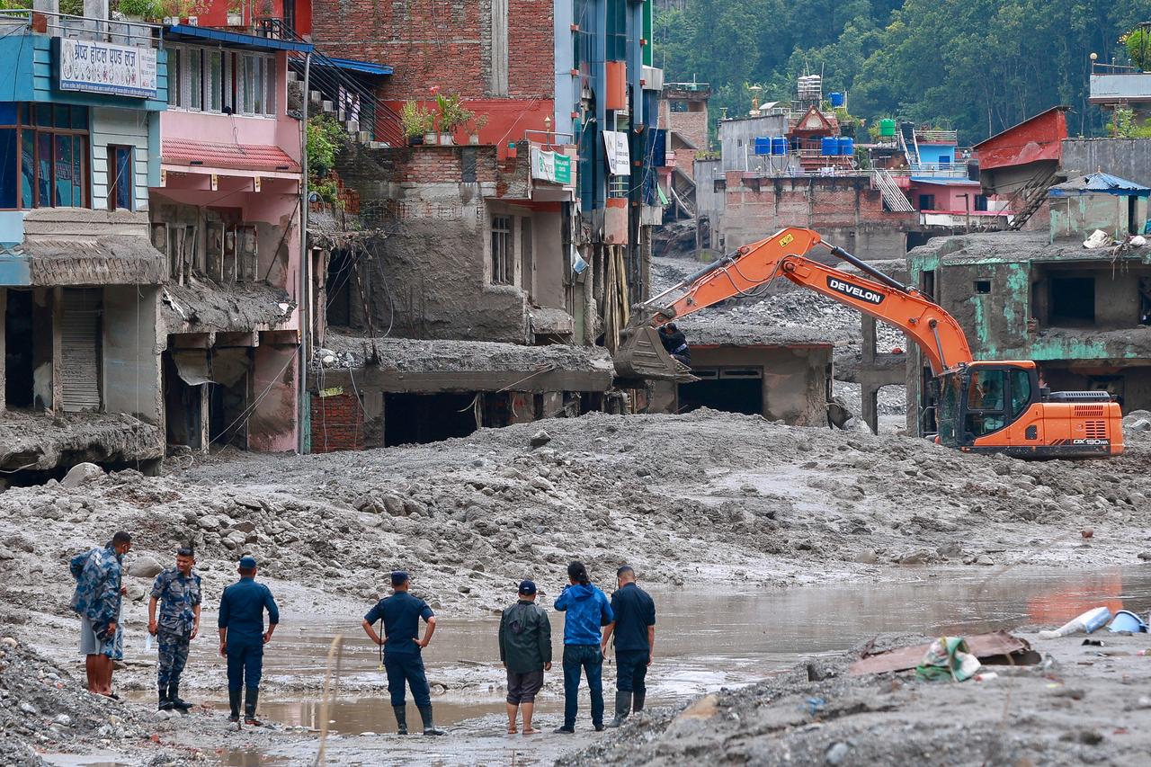 Workers use excavators to clear the mud at the Dhunge Bazaar in Nuwakot, Nepal, Aug. 29, 2026. (AFP Photo)