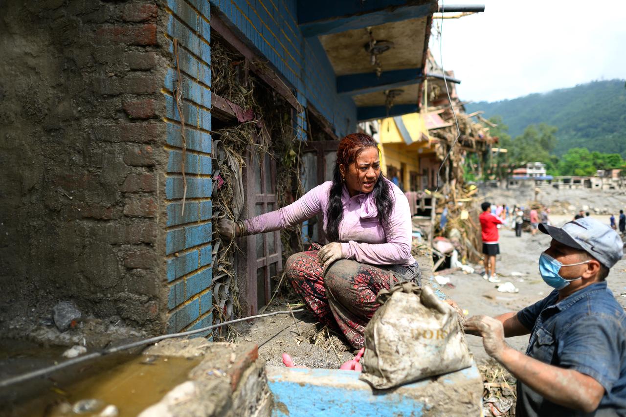 A woman tries to salvage belongings from her house heavily covered in mud in the aftermath of flash floods in Nuwakot, Nepal, Aug. 29, 2026. (AFP Photo)