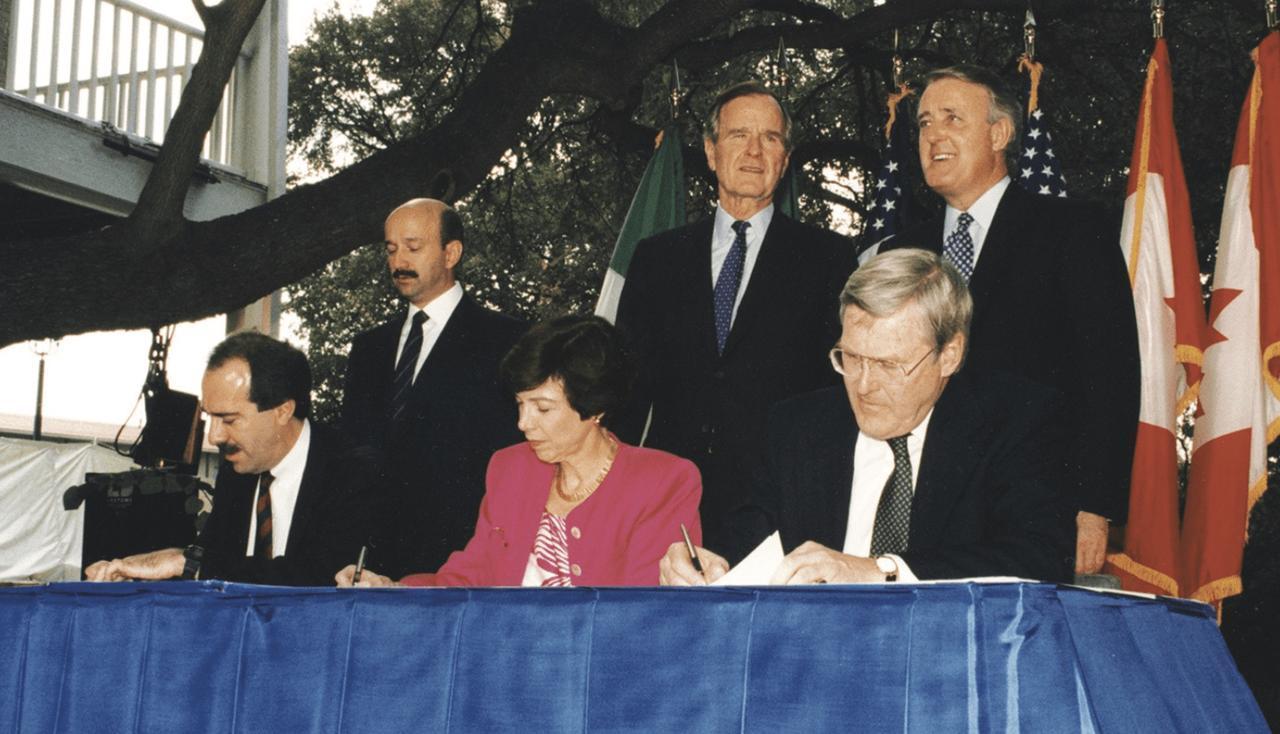 (L/R) President Carlos Salinas, President George H.W. Bush and Prime Minister Brian Mulroney look on as their trade ministers initial the NAFTA agreement in San Antonio, on October 7, 1992. (via George H.W. Bush Presidential Library)