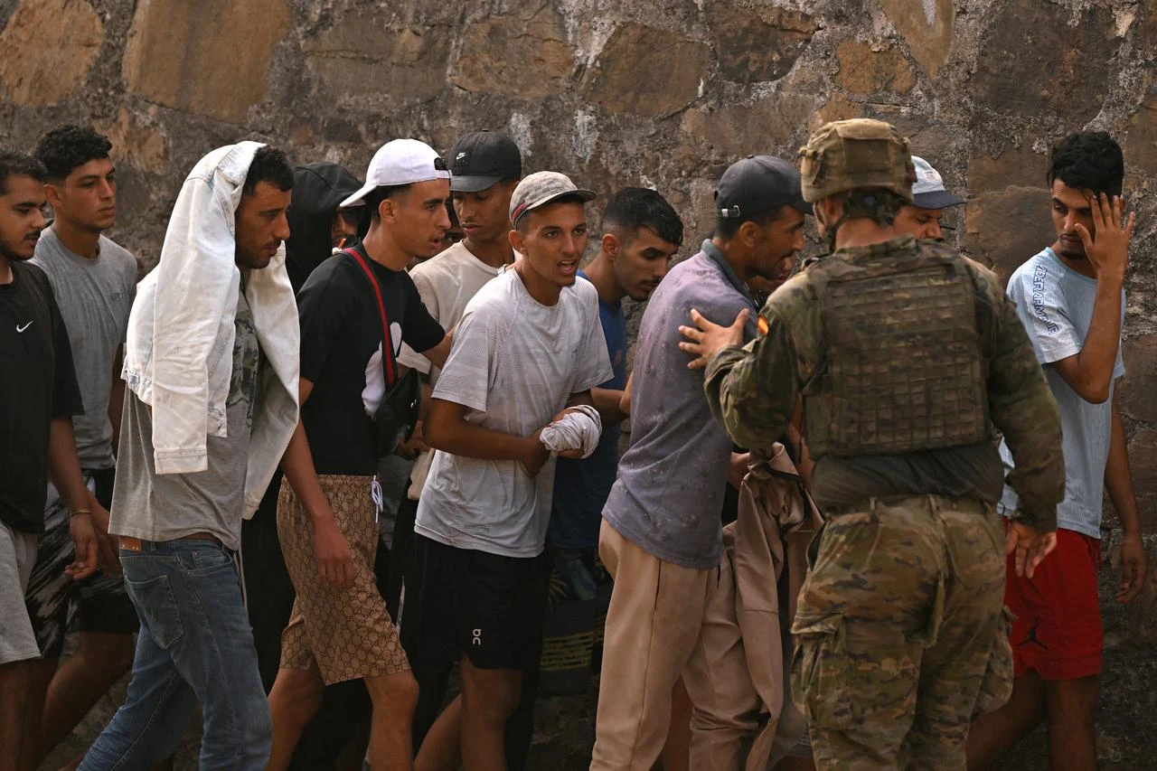 A Spanish soldier controls a group of migrants on their way back towards the Moroccan border, following their illegal crossing into the Spanish enclave of Ceuta, on August 1, 2026. (AFP Photo)