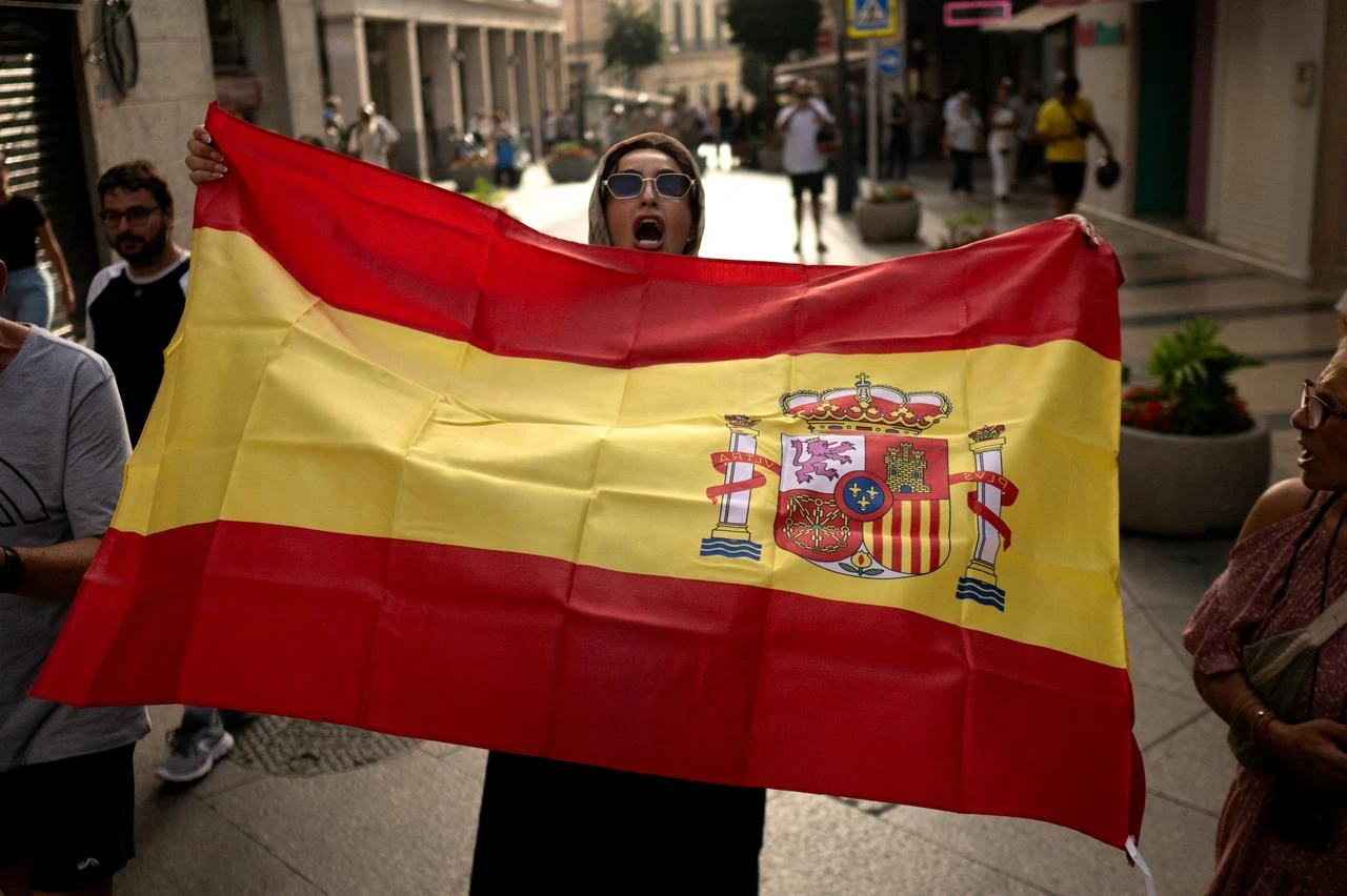 A resident holds a Spanish flag during a demonstration against the visit of Spanish far-right politician Alvise Perez, leader of the Se Acabó La Fiesta (The Party's Over) movement, in the Spanish North African enclave of Ceuta on August 1, 2026. (AFP Photo)