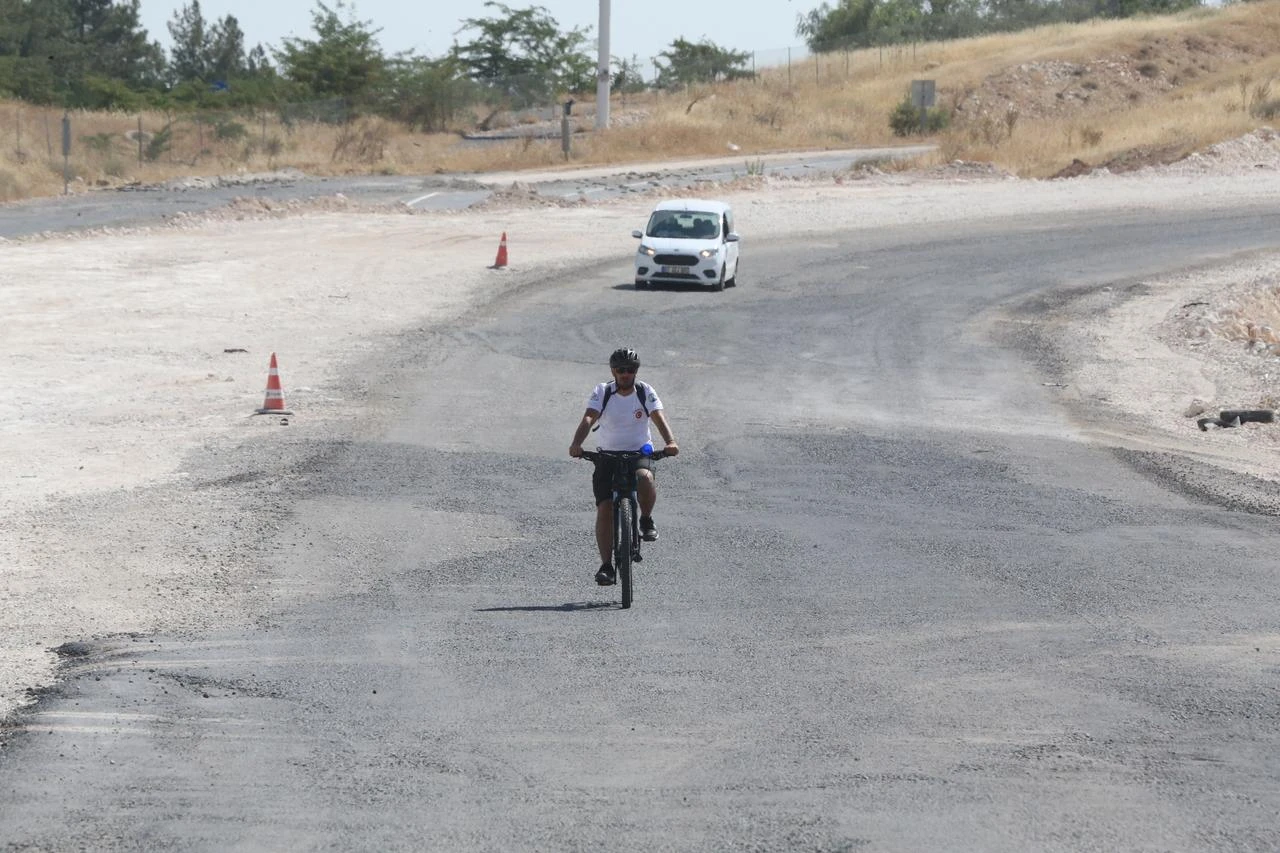 A cyclist rides along the access road to Gobeklitepe as widening work continues to improve transportation to the UNESCO World Heritage site in Sanliurfa, Türkiye. (AA Photo)