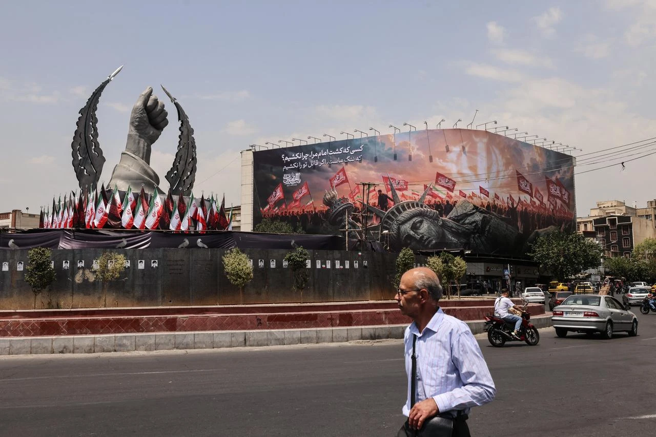 An Iranian man walks past an anti-US billboard at Enghelab Square in central Tehran, August 3, 2026. (AFP Photo)