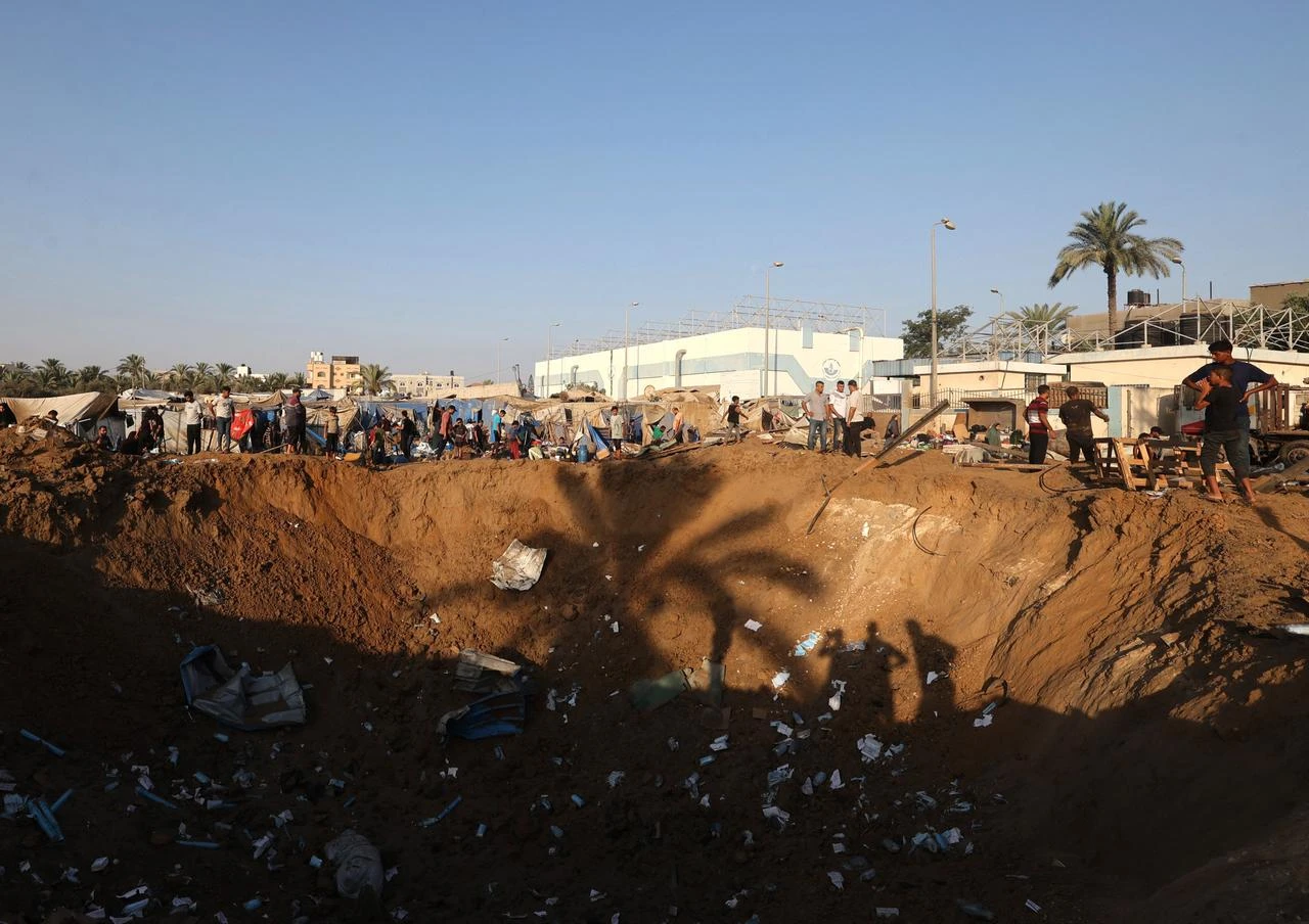 Displaced Palestinians look down into a huge crater following an Israeli airstrike that targeted the nearby medical supplies and pharmaceuticals warehouse of Al-Aqsa Martyrs Hospital, in Deir al-Balah, central Gaza Strip, Aug. 1, 2026. (AFP Photo)
