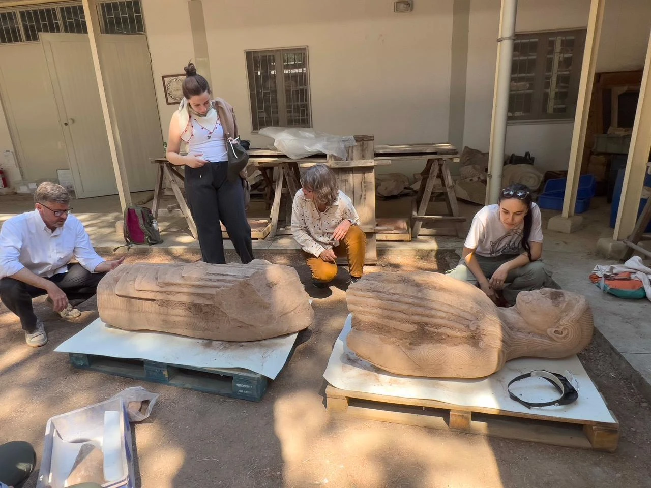 Archaeologists examine the two main sections of the monumental young male statue after they were safely lifted from the excavation site. (AA Photo)