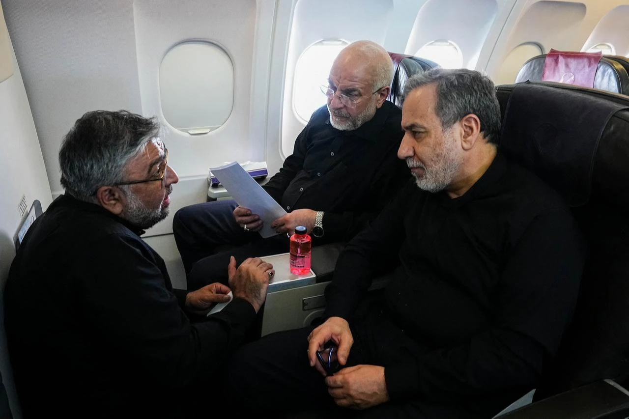 Iranian Parliament Speaker and Iran negotiating team head Mohammad Bagher Ghalibaf (C) and Iranian Foreign Minister Abbas Araghchi (R) speaking with a member of the Iranian delegation aboard a flight en route to Zurich on June 21, 2026. (AFP Photo/Office of Iranian Parliament Speaker/HO)