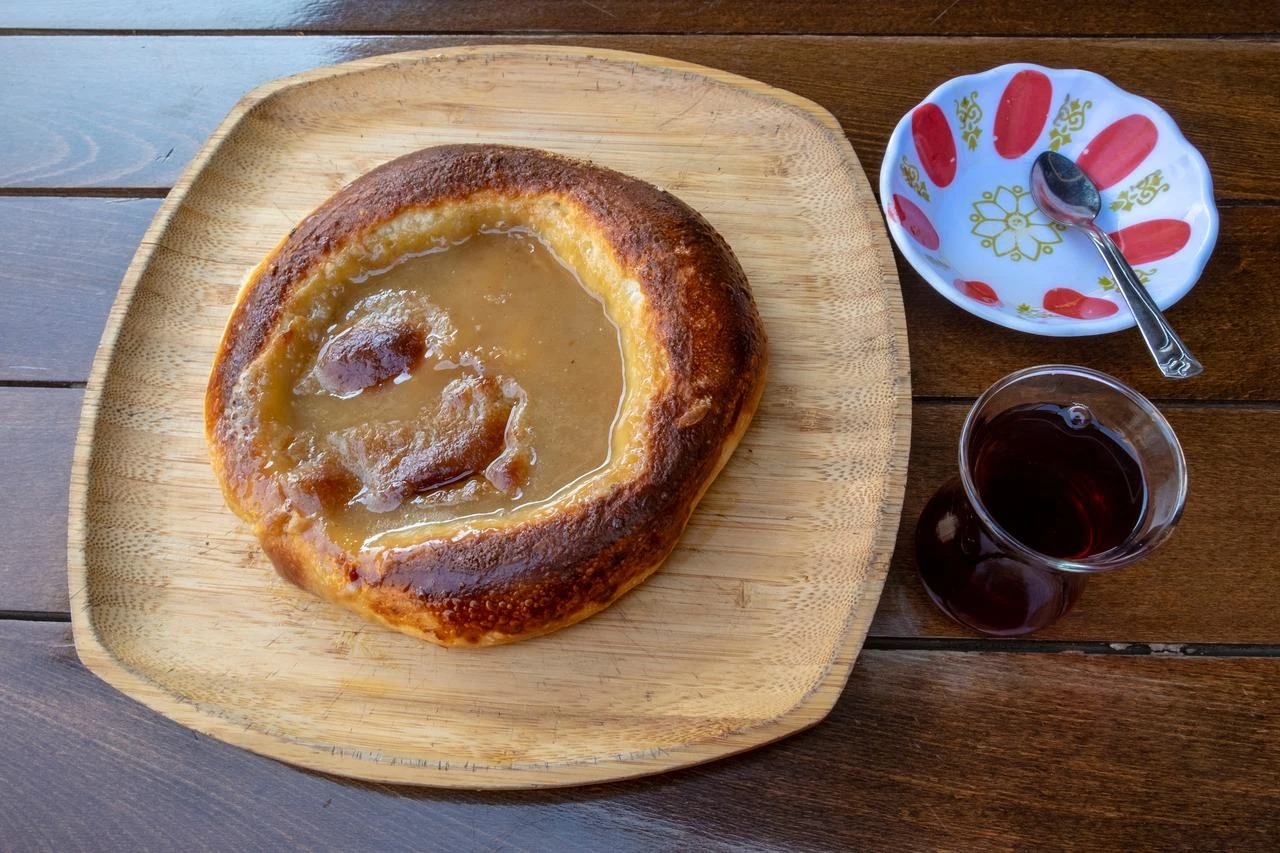 Tahinli pide, a sweet Turkish flatbread topped with tahini, is served with a glass of traditional tea. (Adobe Stock Photo)