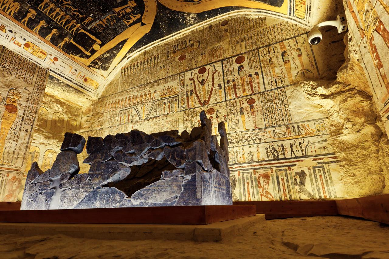 Painted funerary scenes surround a stone sarcophagus inside an ancient Egyptian tomb in the Valley of the Kings, Luxor, Egypt. (Adobe Stock Photo)