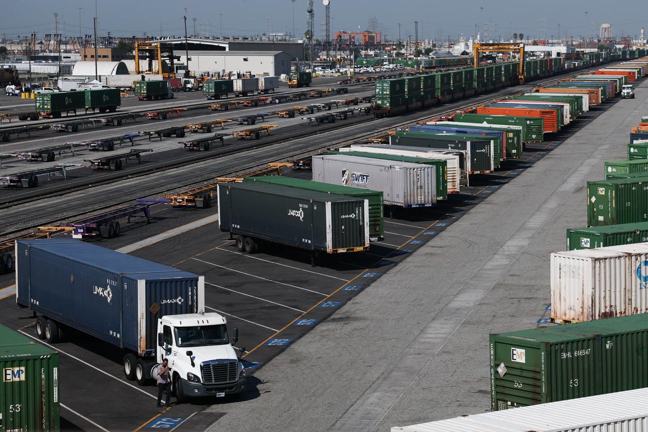 A person walks besides a semi-truck parked at a cargo shipping container on a rail yard in Commerce, California on August 26, 2026. (AFP Photo)